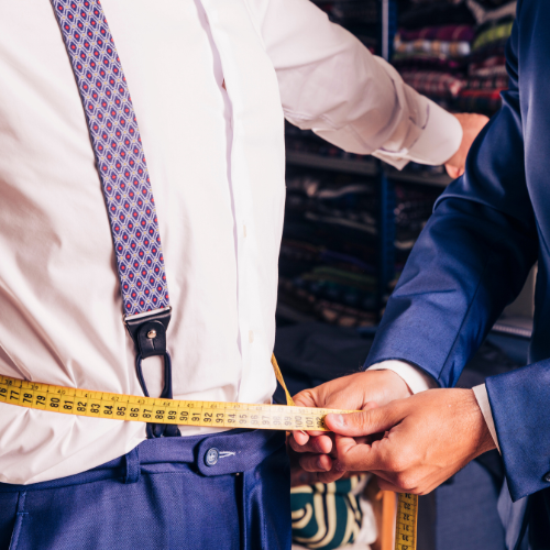 A tailor taking measurements for a 3-piece suit at a client's home